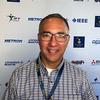 Paulo Costa wears glasses, a lanyard, and a gray shirt